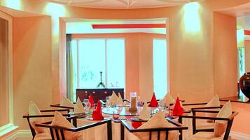 A dining area with a geometric patterned carpet, a round table with chairs, and a ceiling with a unique design.