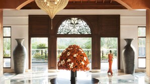 A lobby with a large vase of flowers, a polished floor, and a person in the background. - Taj Bentota Resort & Spa (Bentota)