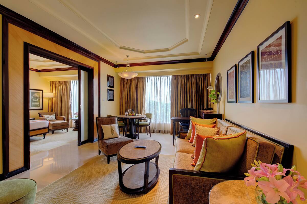 A spacious hotel room with a living area, a dining table, and a separate bedroom with a large bed.