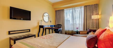 Una habitación de hotel con cama, escritorio, silla, televisión, lámpara y cortinas.