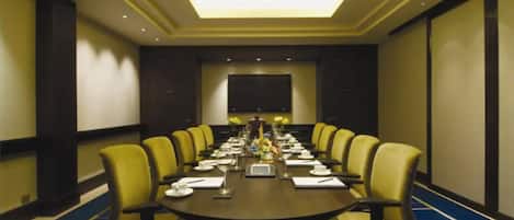 A conference room with a long table, yellow chairs, and a blue carpet.