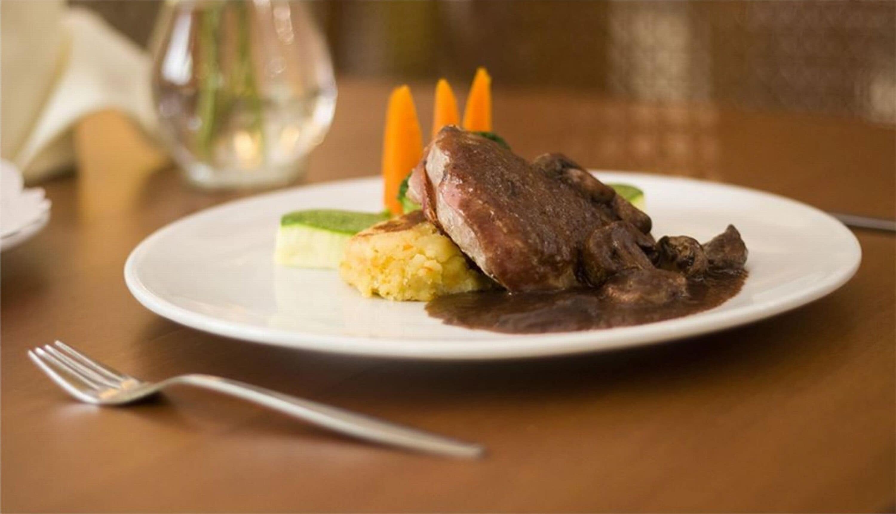 Ein Teller mit Fleisch, Kartoffelpüree und Karotten.