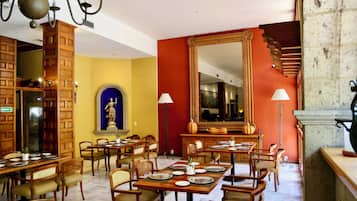 Un comedor con varias mesas y sillas, un espejo grande y una escalera.