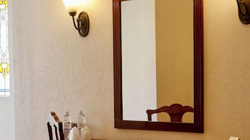 Un escritorio de madera con un espejo, una silla y una pequeña mesa con una lámpara.