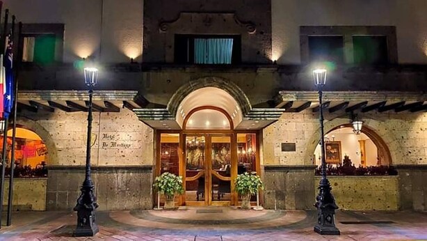 Fachada de hotel de piedra, con ventanas en arco y una puerta central.