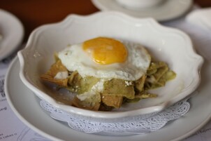 En skål med nachos, drysset med et spejlæg og cremefraiche.