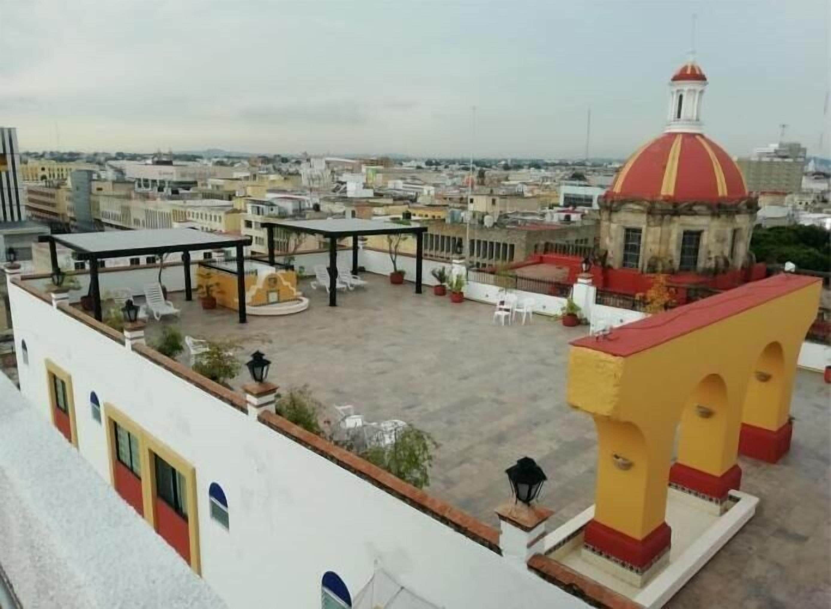 A rooftop terrace with outdoor seating, a central fountain, and a distinctive red and yellow dome structure.