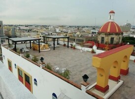 Terraza en la azotea con mobiliario exterior, una fuente central y una estructura cúpula distintiva de color rojo y amarillo.