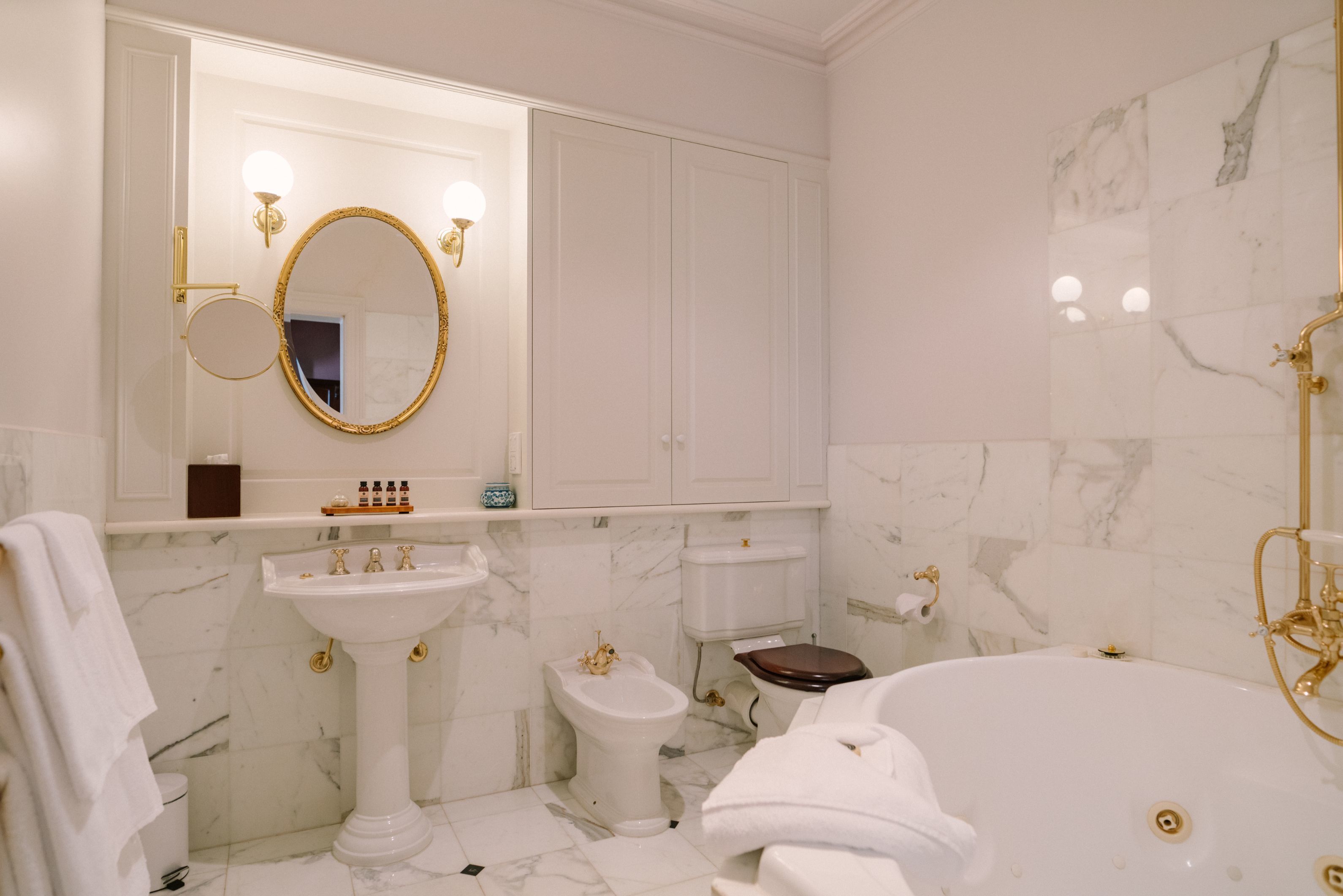 Een badkamer met een wastafel op voet, een toilet, een douchetoilet en een vrijstaand bad.