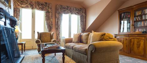 A cozy living room with a sofa, armchair, and a fireplace.