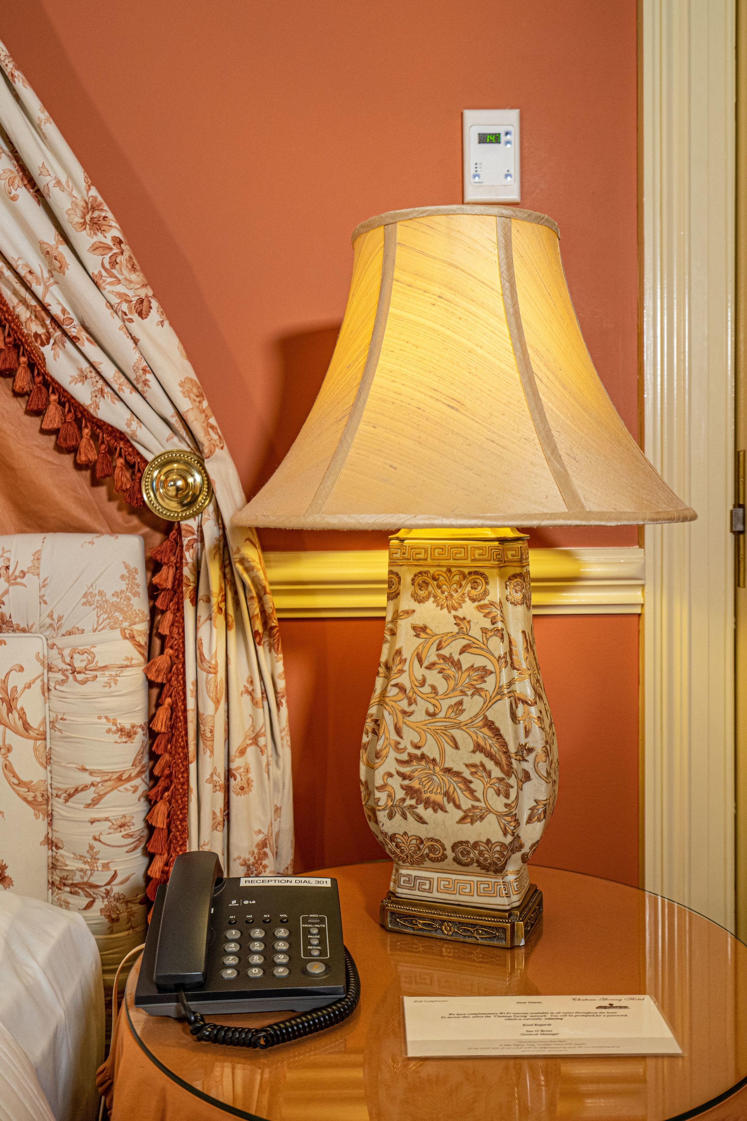 Una habitación con mostrador de recepción, teléfono y lámpara con base decorativa.