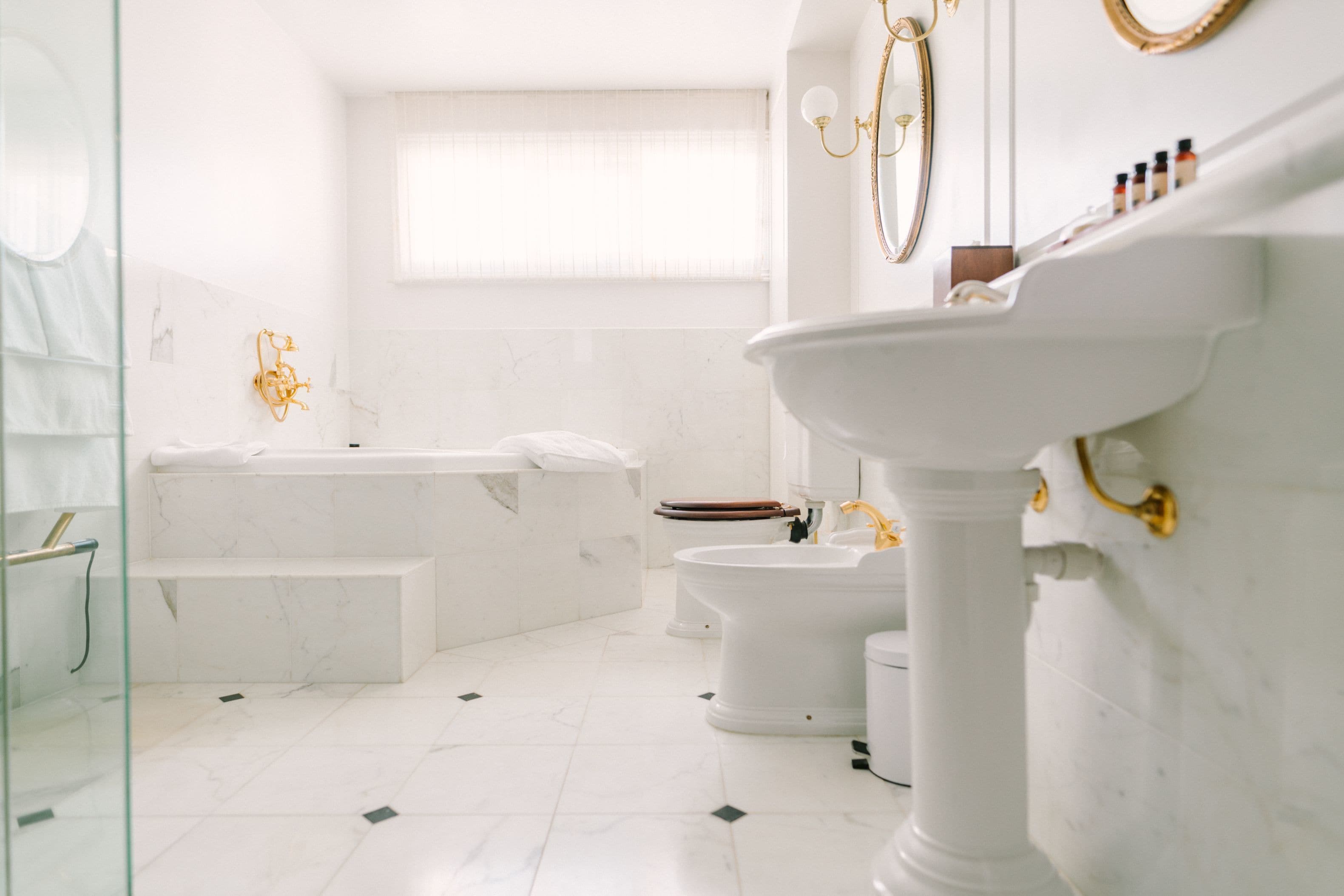 Un baño moderno con bañera, inodoro y lavamanos sobre pedestal.