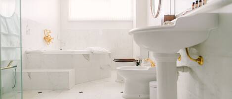 Un baño moderno con bañera, inodoro y lavamanos sobre pedestal.