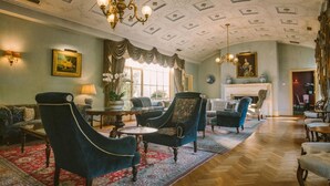 A spacious lounge with elegant furniture, a fireplace, and a decorative ceiling. - Chateau Yering Hotel (Yering)