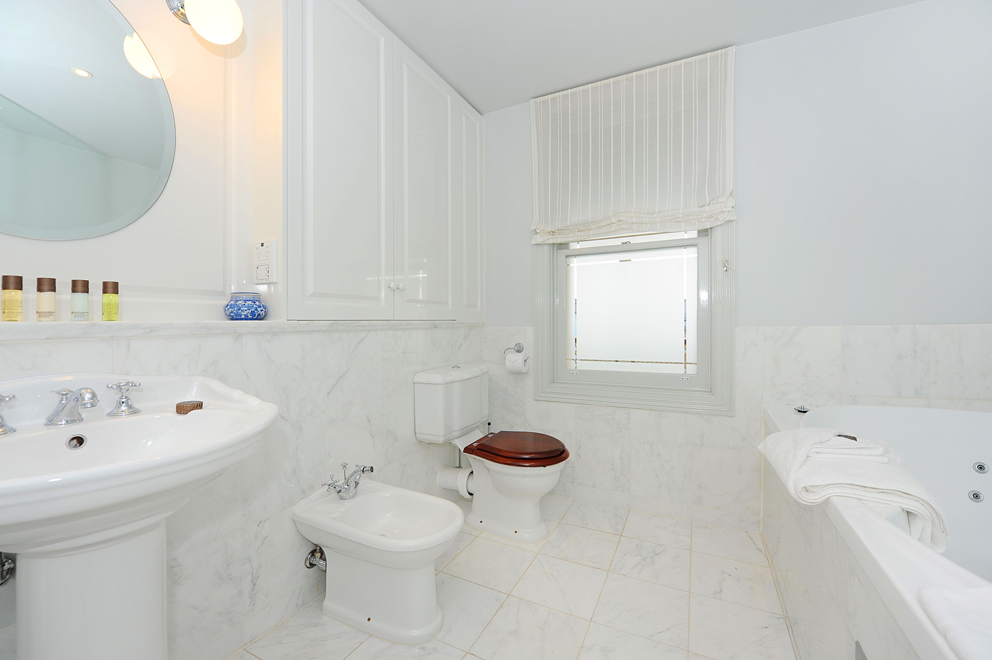 A bathroom with a sink, bidet, toilet, and bathtub.