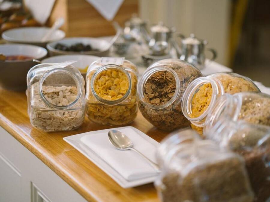 Un bufé de desayuno con diversos alimentos en frascos de vidrio sobre una mesa de madera.