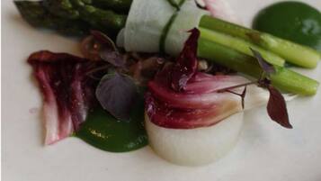 Un plato con una variedad de verduras, incluyendo espárragos, hojas verdes y hojas moradas.