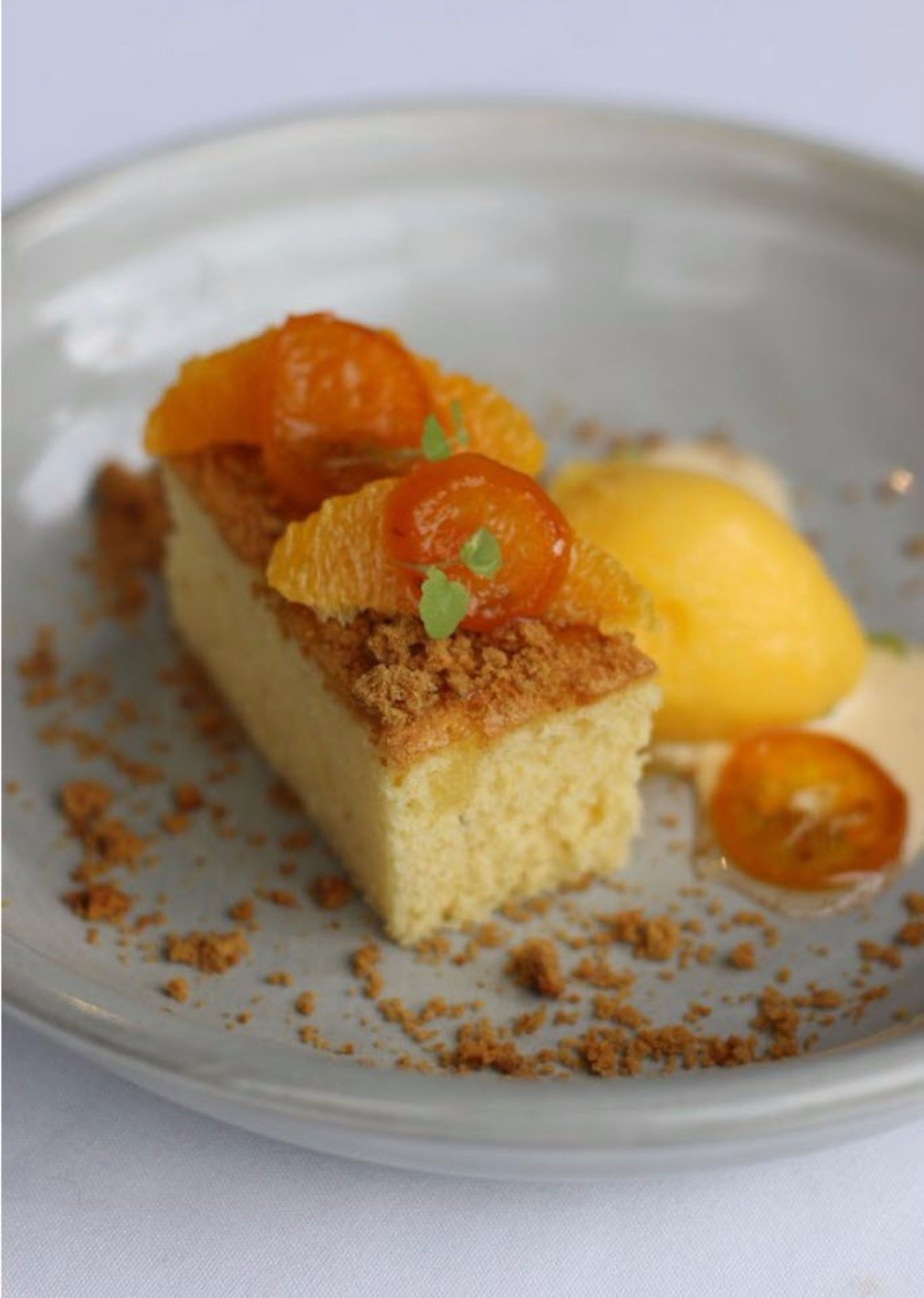 Un postre en un plato con migas y una rodaja de limón.