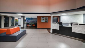 A spacious lobby with a reception desk, seating area, and a mural on the wall.