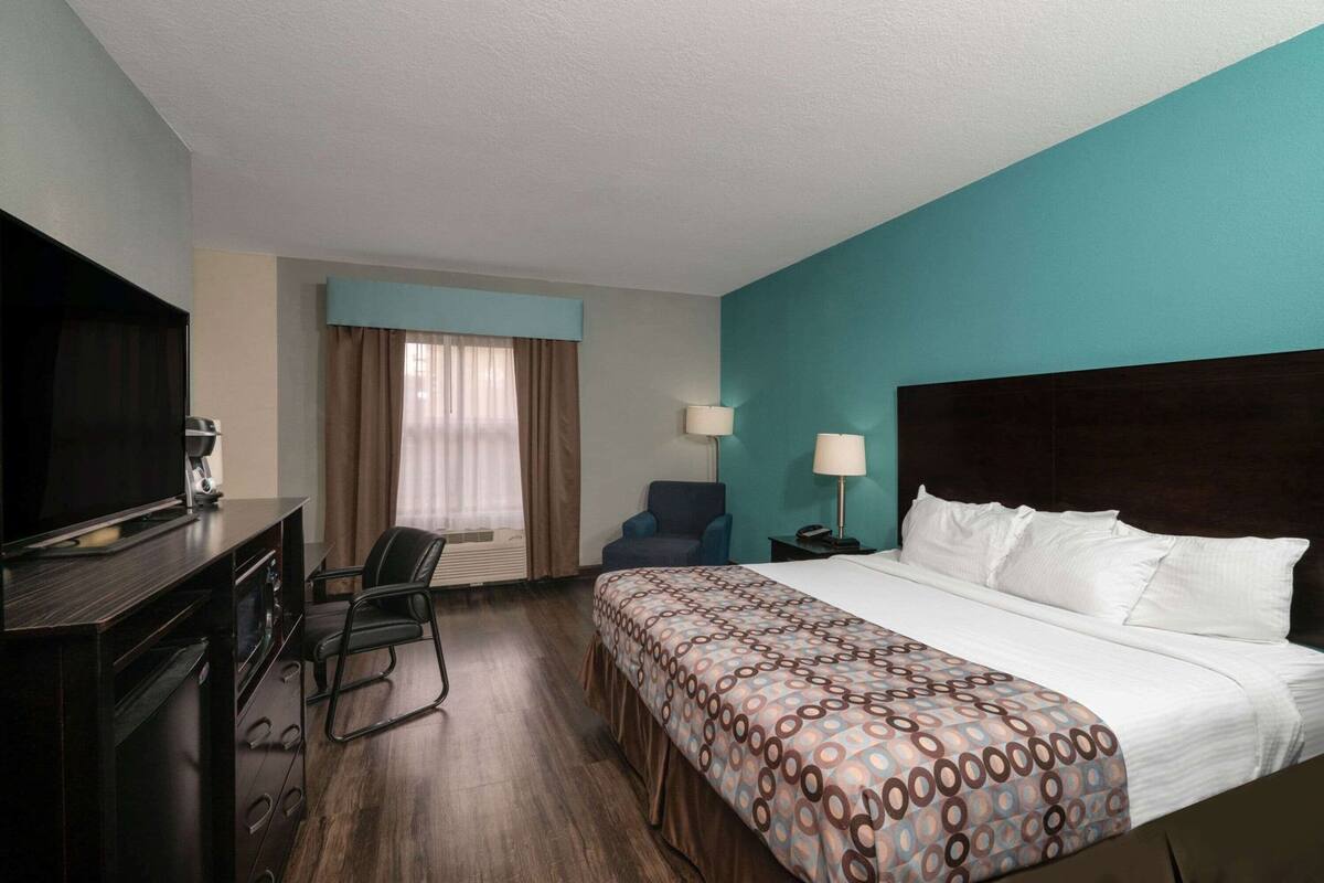 Una camera d'albergo con un letto, una scrivania, una sedia, una televisione e una macchina per il caffè.