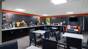 A restaurant with a counter, seating area, and a television screen.