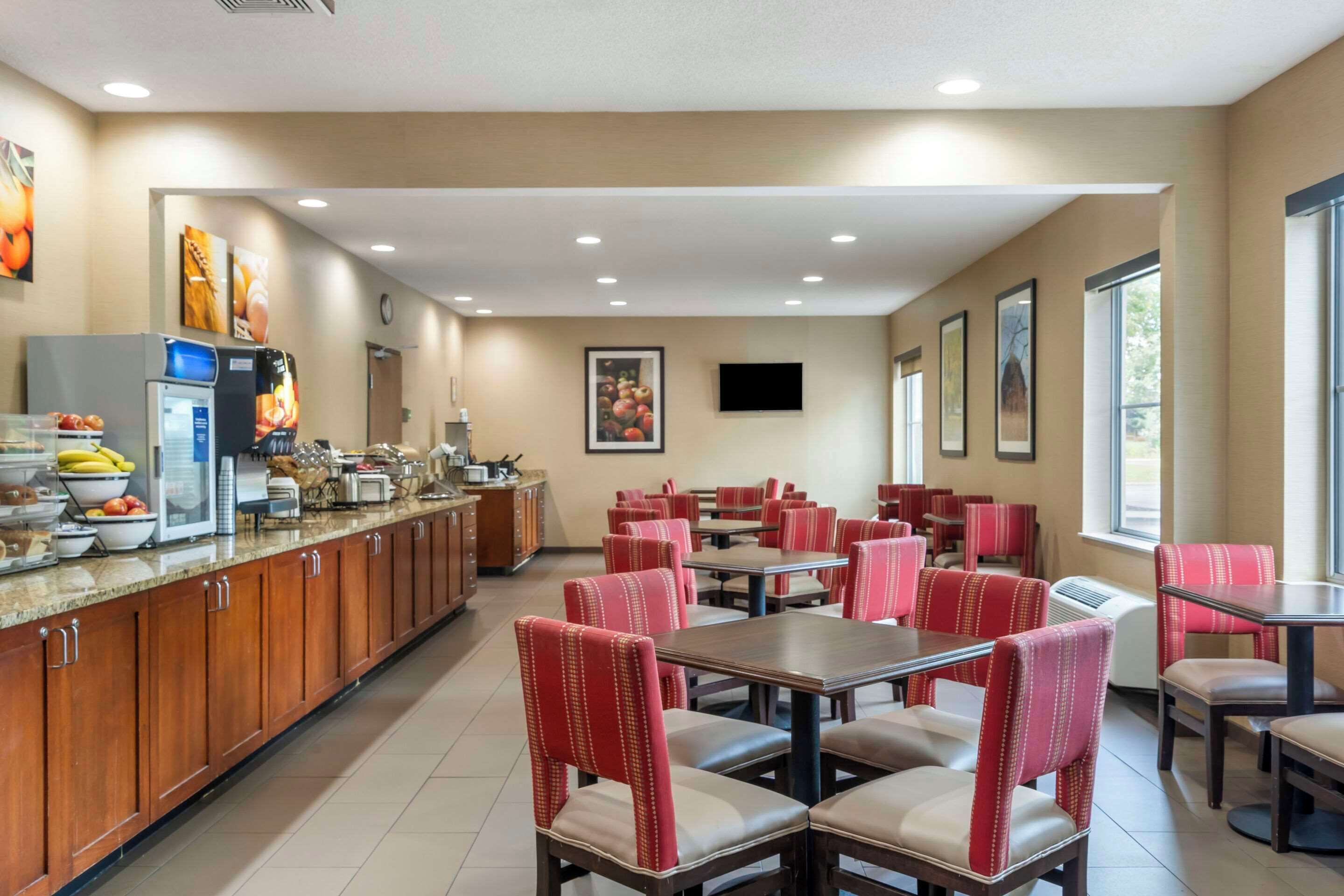 A restaurant with a long counter, red upholstered chairs, and a television mounted on the wall.