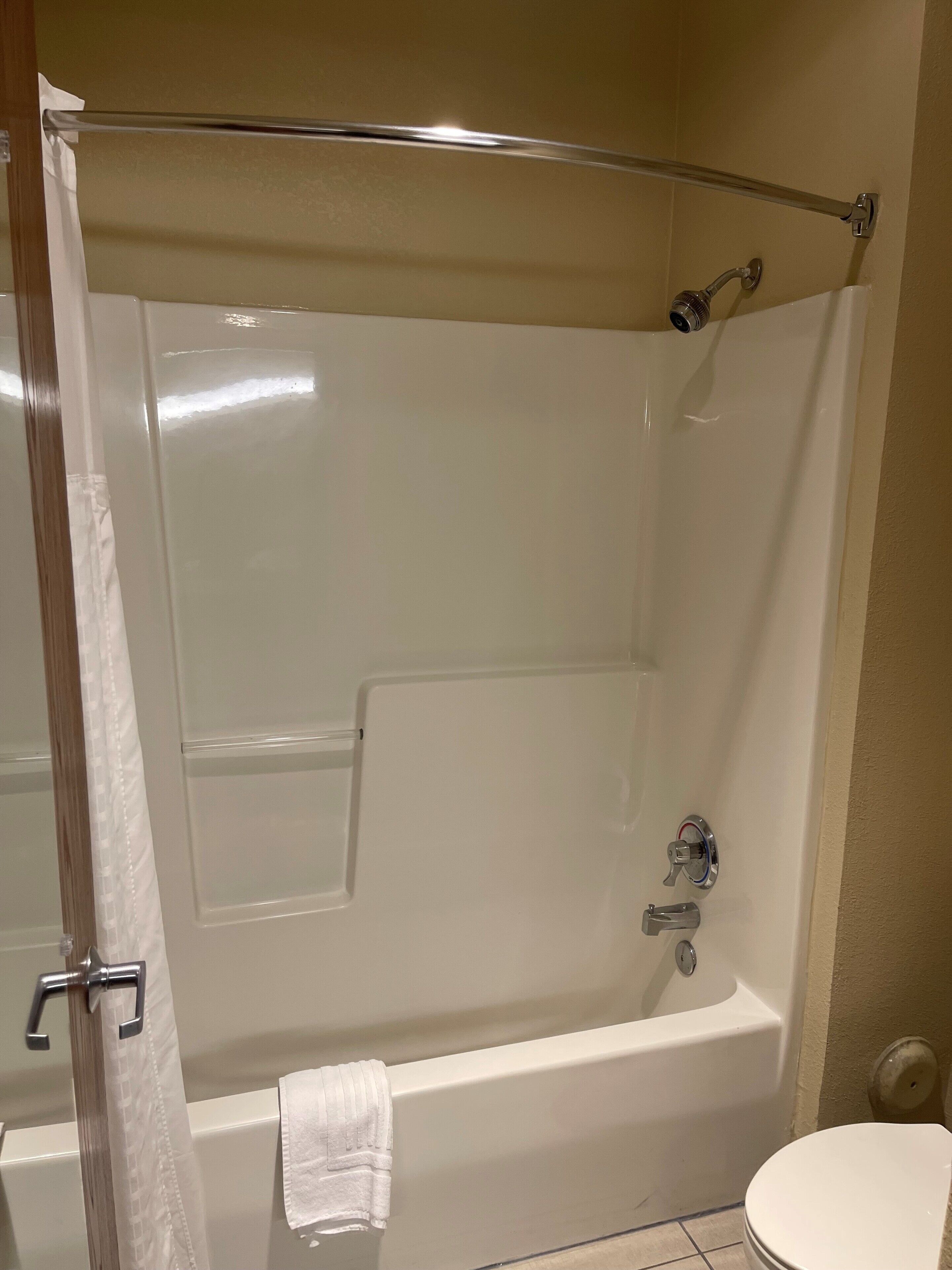 A bathroom with a bathtub, toilet, and shower curtain.