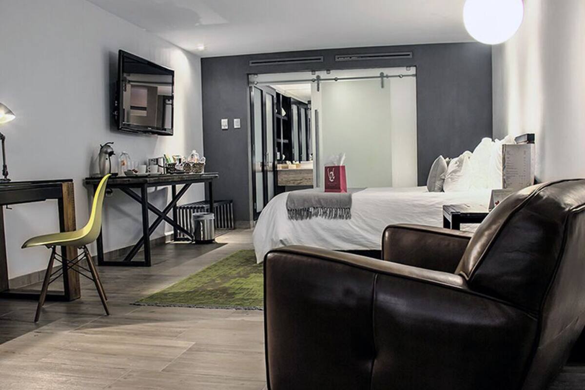 A modern hotel room with a bed, a desk, a chair, and a TV.