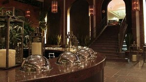 Um hall de entrada com balcão de recepção de mármore, cúpulas de vidro e uma escadaria que dá acesso aos andares superiores.