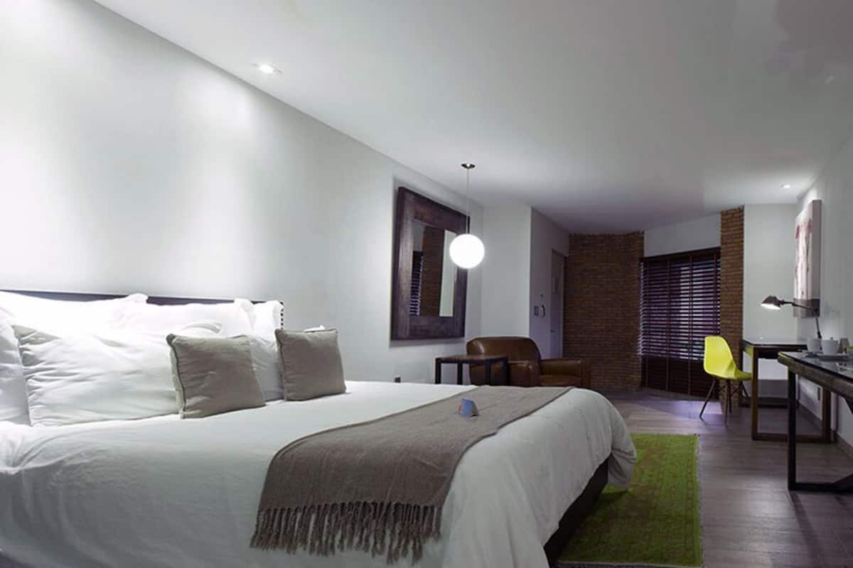 A modern bedroom with a large bed, a desk, and a chair.