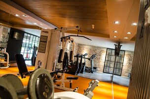 Un gimnasio con equipo de ejercicio, una banca de pesas y un espejo.