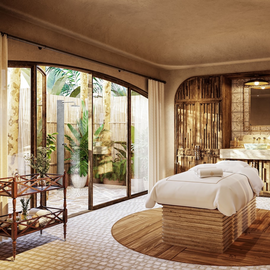 A spacious bedroom with a large bed, a wooden headboard, a vanity with a mirror, and a view of a tropical garden through large sliding doors.