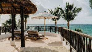 A balcony with a thatched roof, two lounge chairs, a table, and a view of the ocean. - Maroma, A Belmond Hotel, Riviera Maya (Playa del Carmen)