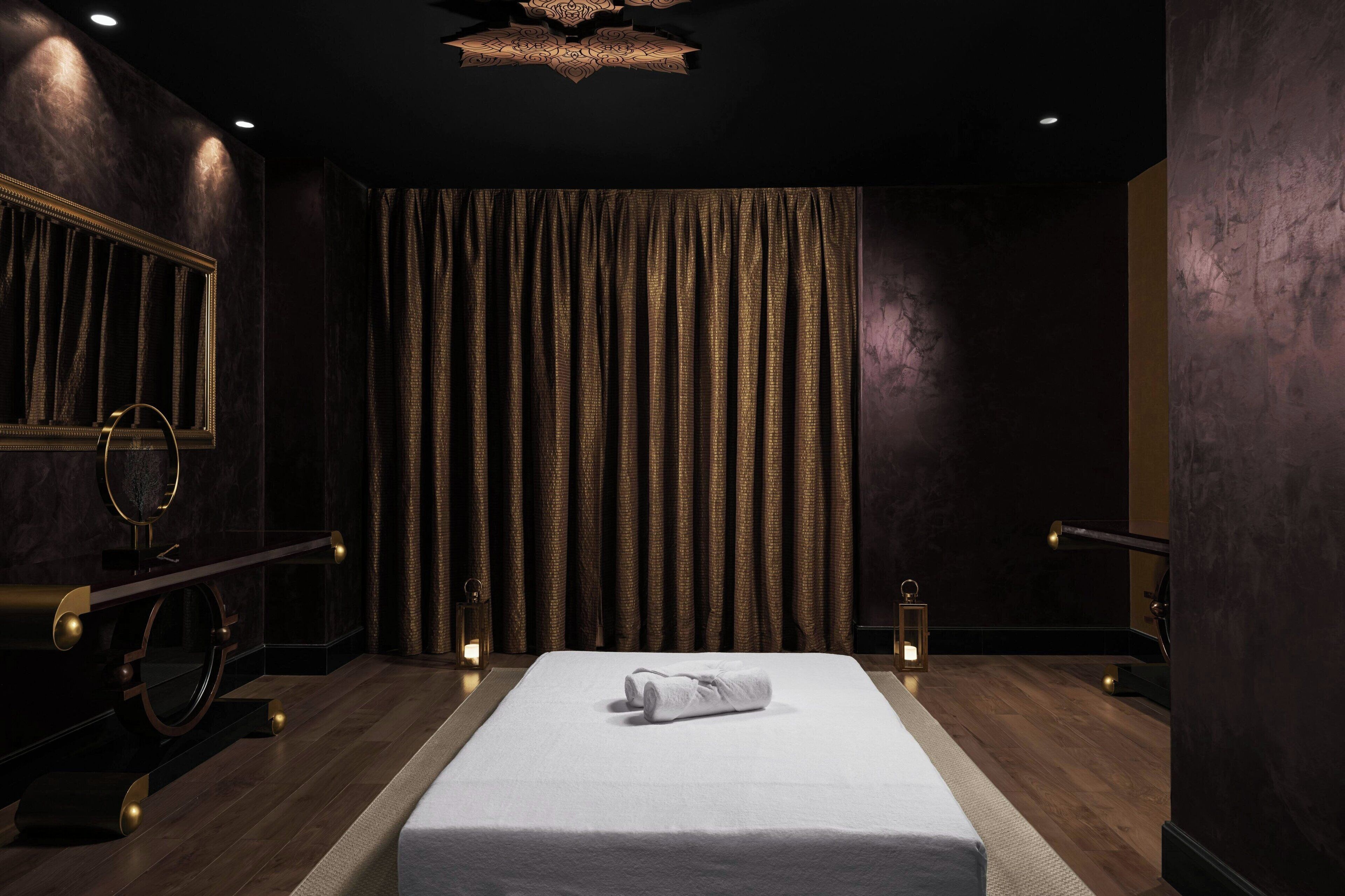 Quarto de hotel com uma cama grande, um espelho, uma penteadeira e uma cortina.