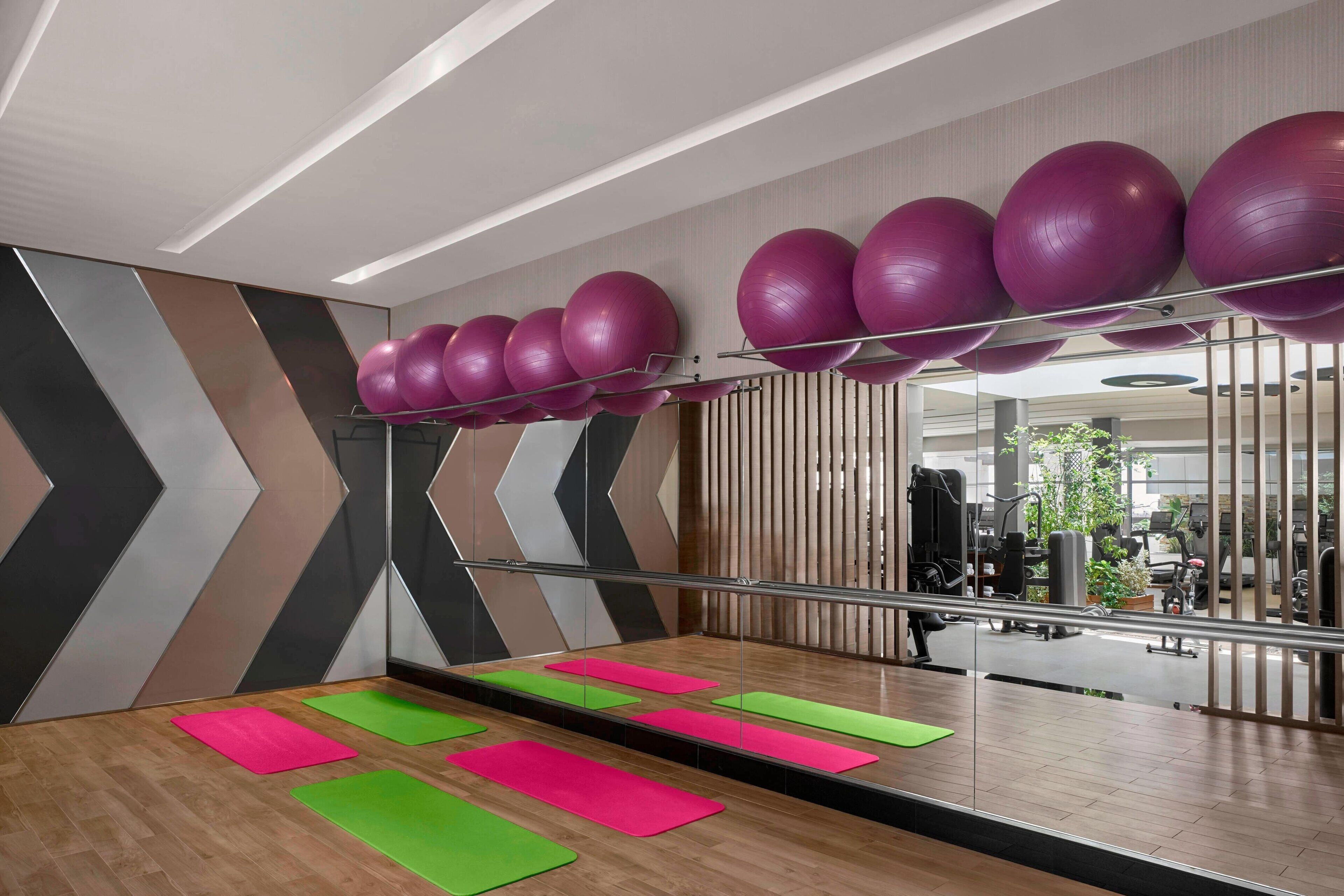 Een sportschool met trainingsapparatuur, spiegels en matten.