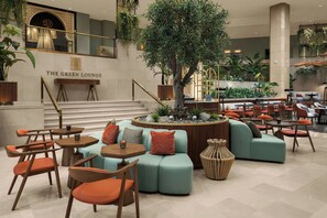 Un vestíbulo con una zona de estar central, una escalera y un cartel que dice 'THE GREEN LOUNGE'.
