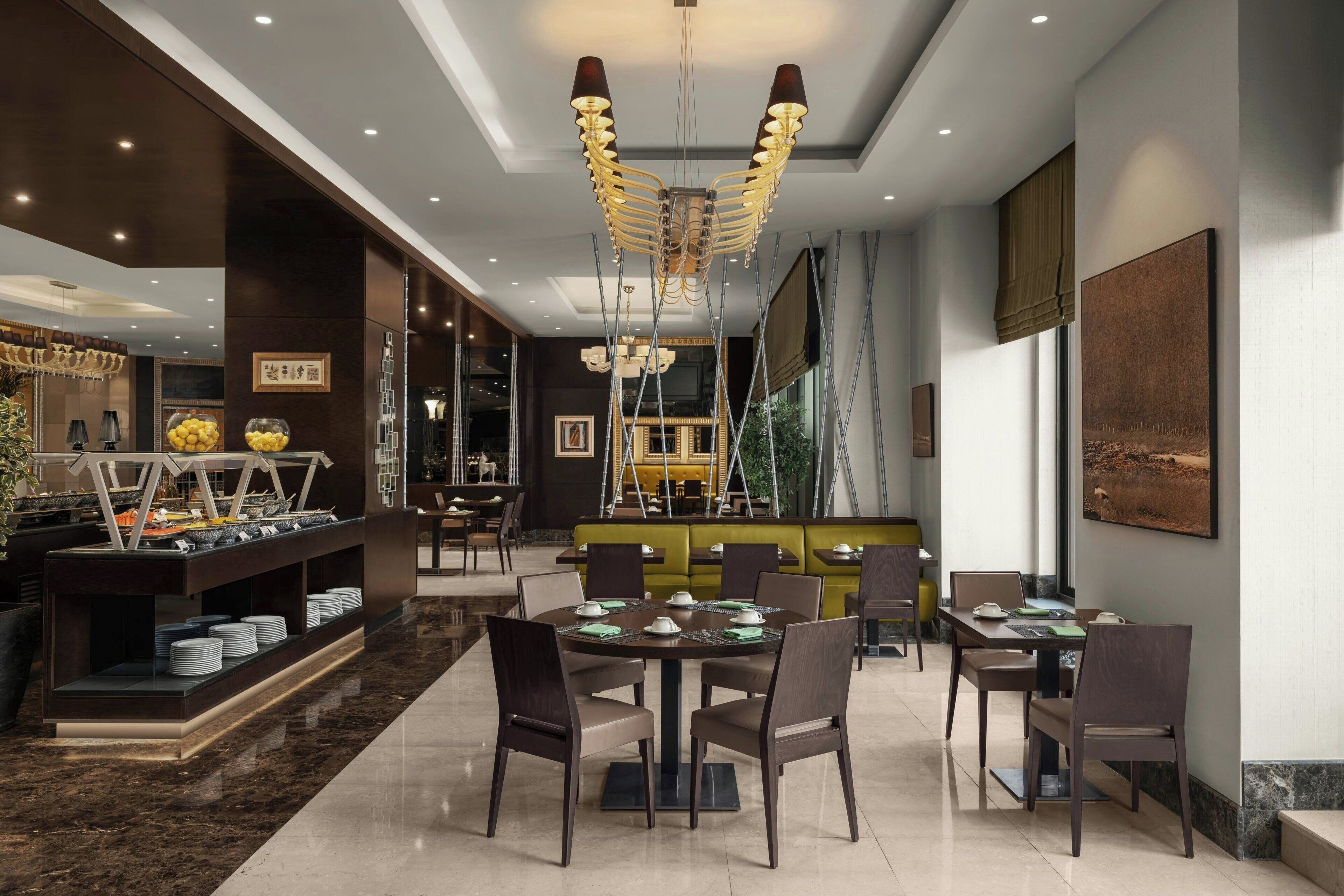 A modern dining area with round tables, chairs, and a central chandelier.