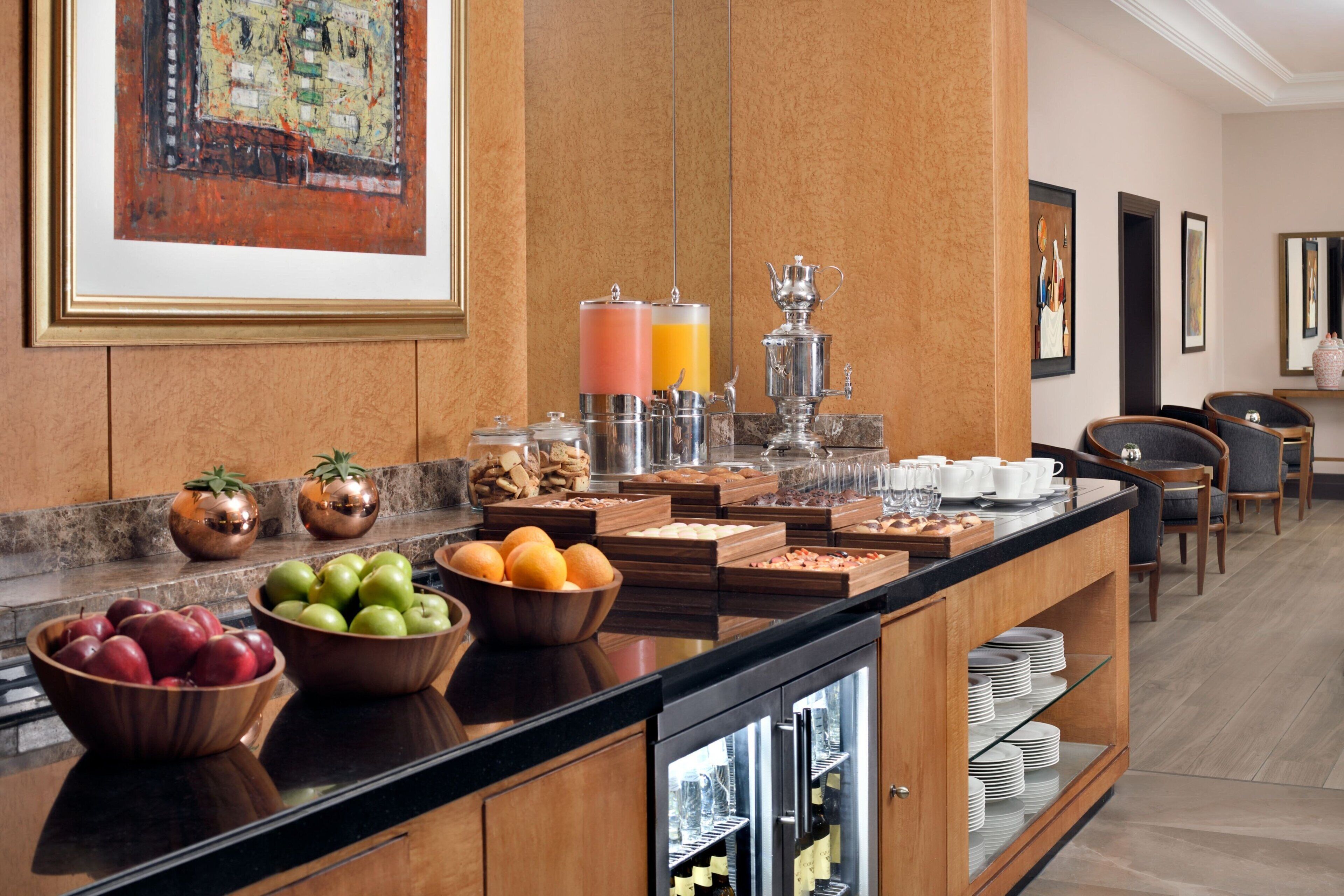 A breakfast bar with fruits, beverages, and a coffee station.