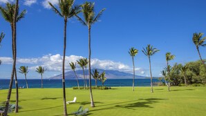 A golf course with palm trees and a view of the ocean. - Kihei Surfside - Maui Condo & Home (Kihei)