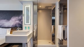 A modern bathroom with a glass-enclosed shower, a white sink, and a vanity with a mirror.
