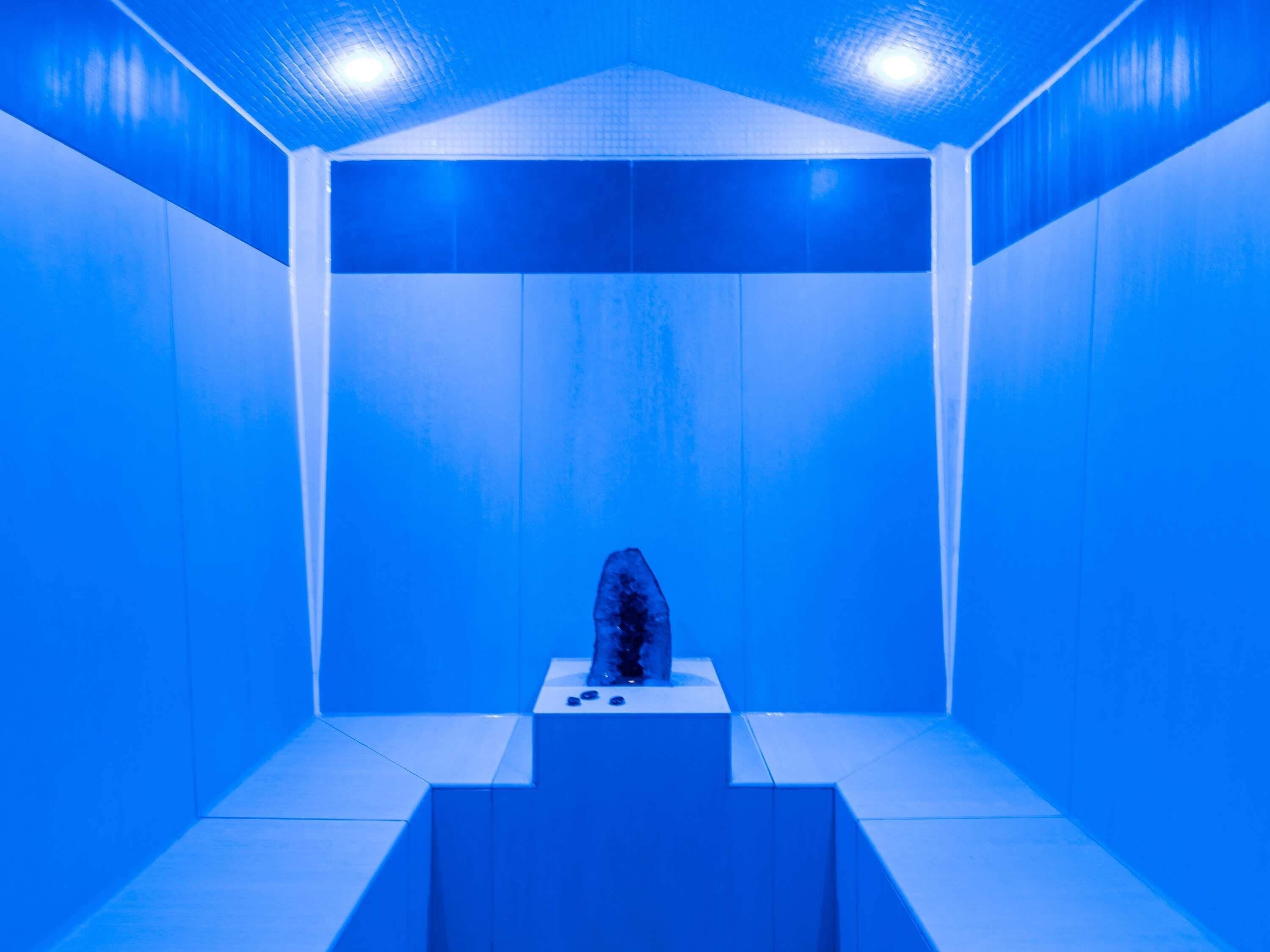 A room with a blue color scheme, a central sculpture, and a tiled floor.