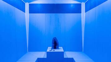 A room with a blue color scheme, a central sculpture, and a tiled floor.