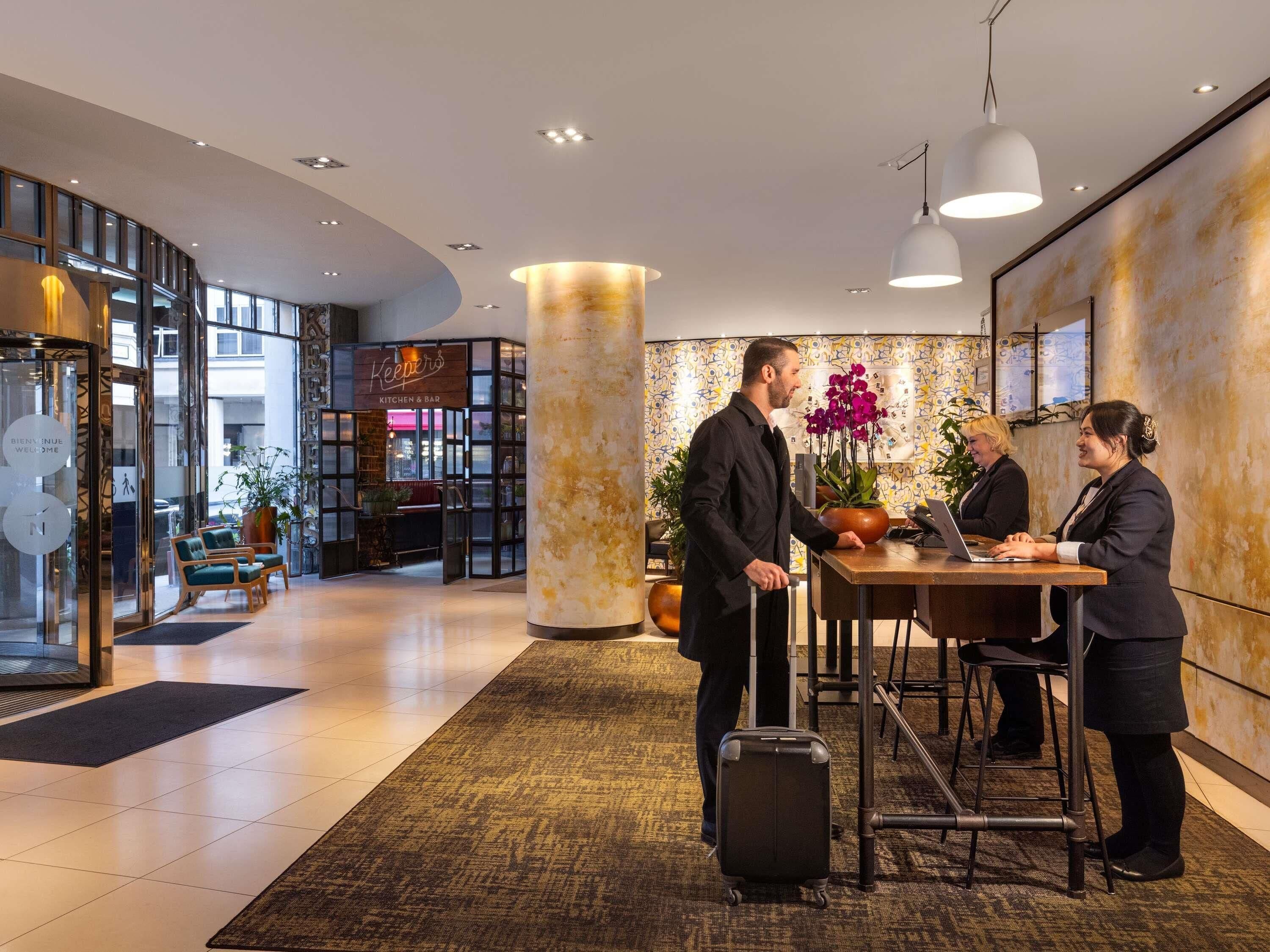 A hotel lobby with a reception desk, a bar, and a large pillar.