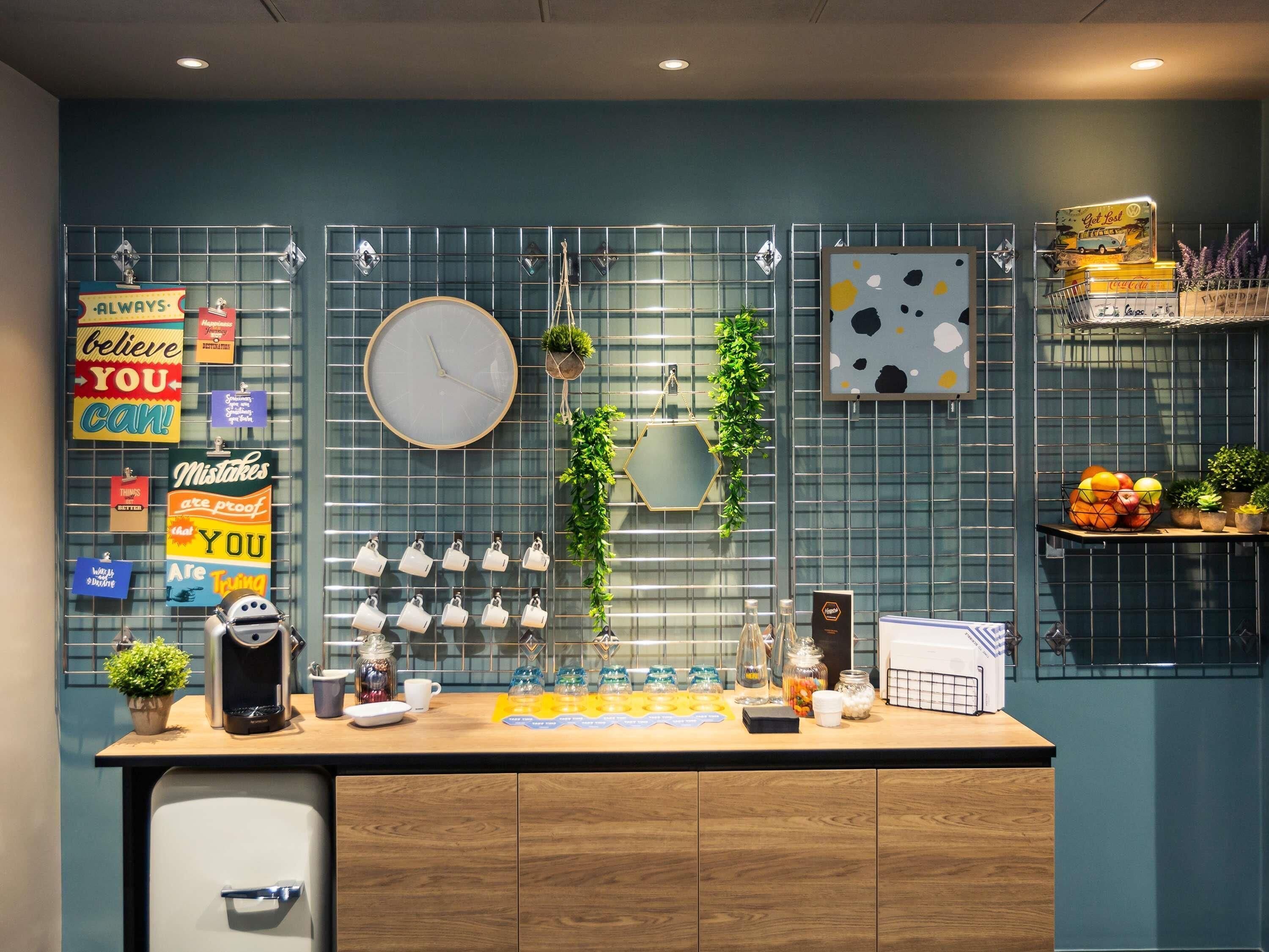 A modern kitchen with a coffee machine, tea kettle, and various mugs on the counter.