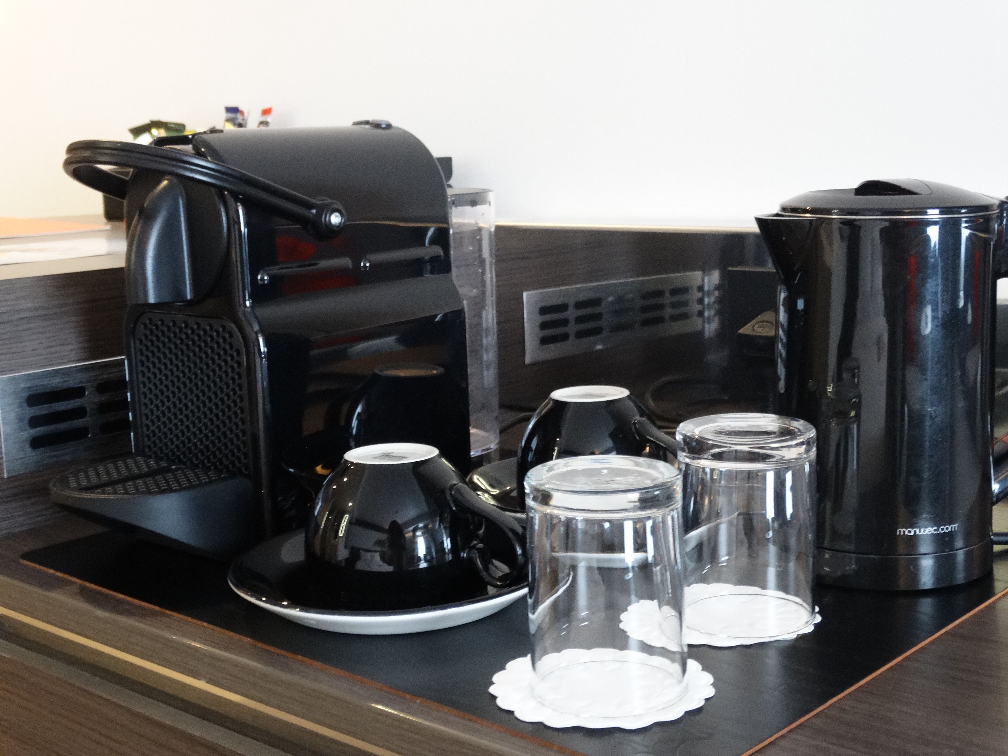 A coffee station with a coffee maker, cups, and a thermos on a wooden counter.