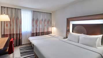 Habitación de hotel con una cama grande, un escritorio, una silla y una cortina estampada.