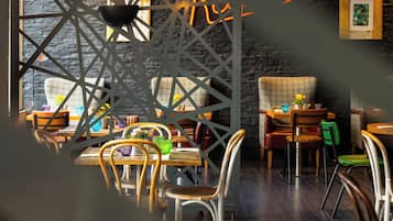 A restaurant interior with a modern design, featuring a stone wall, wooden tables, and chairs.