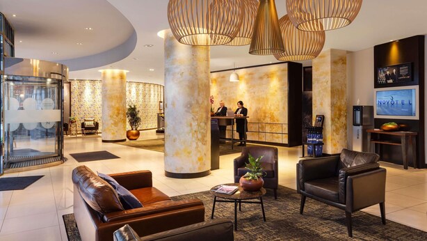 A modern hotel lobby with leather seating, a reception desk, and decorative lighting.