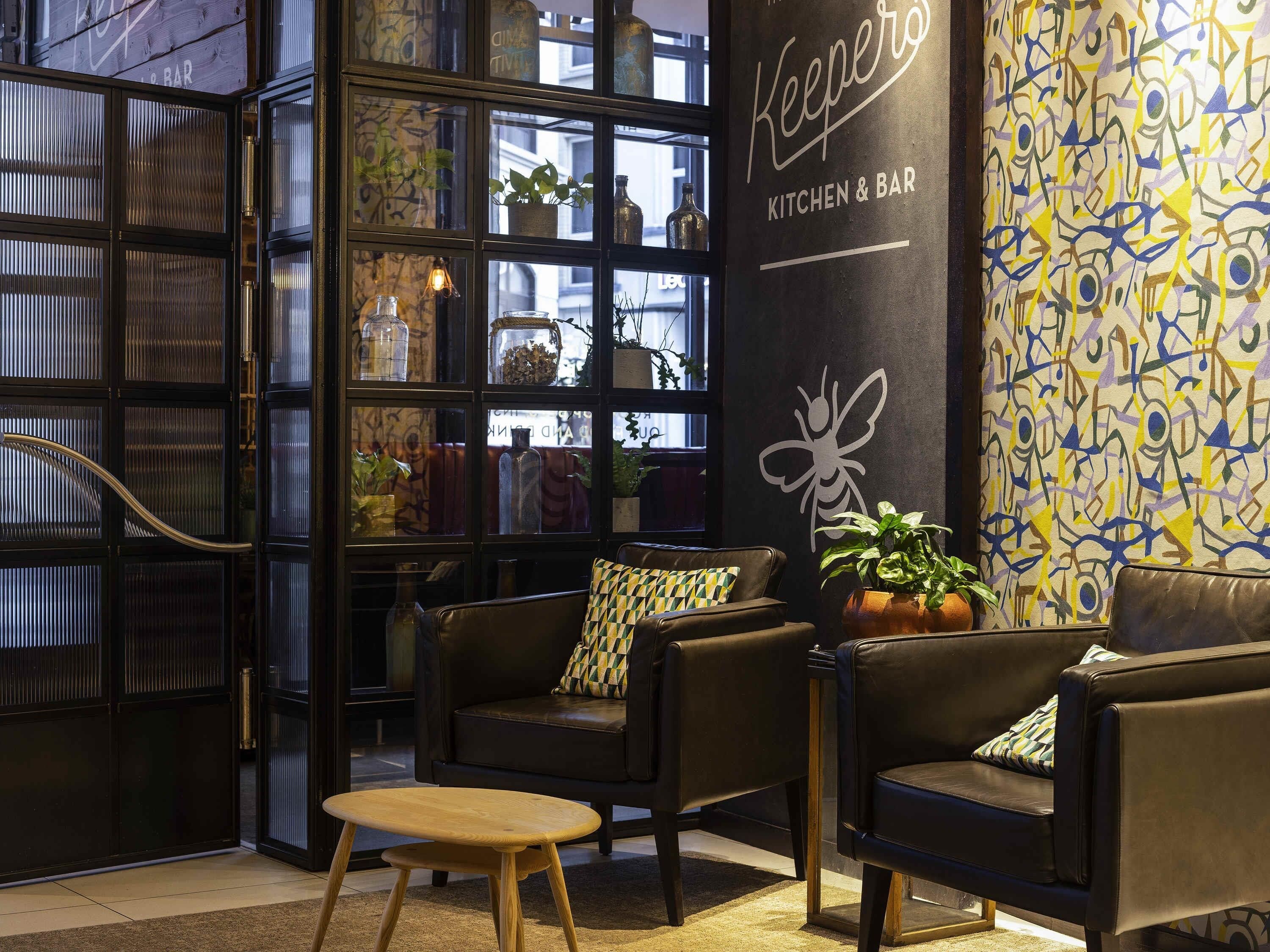 A cozy interior with leather sofas, a wooden table, and a glass partition with shelves.