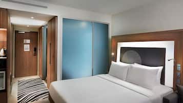 A hotel room with a bed, a desk, a wardrobe, and a bathroom.
